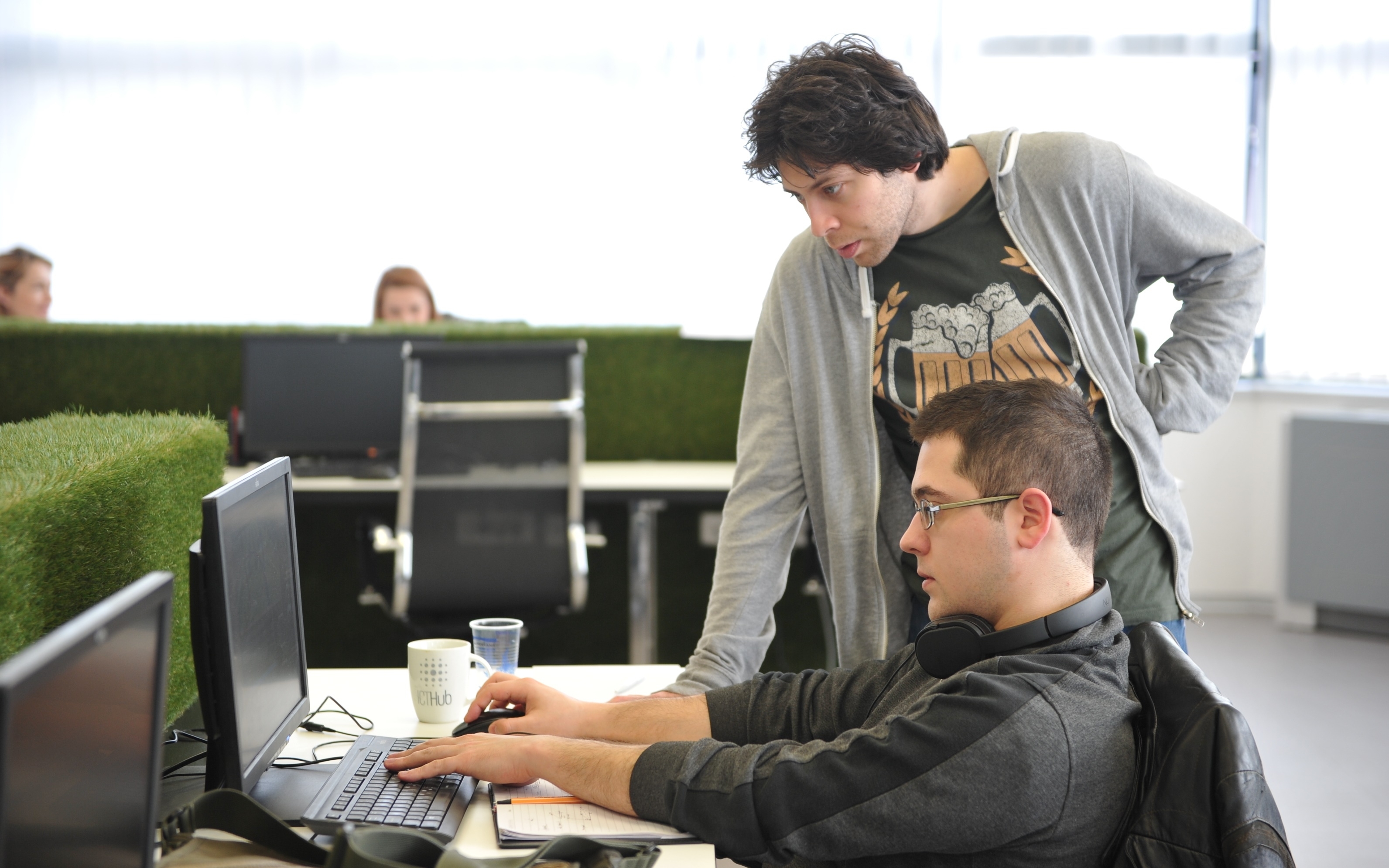 Zwei Mitarbeitende im Büro vor einem Computer.